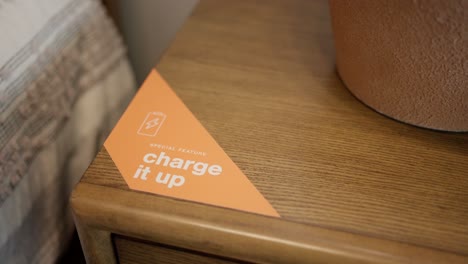 Sticker-graphic-on-brown-wood-nightstand-says-'Charge-It-Up'-with-built-in-charger