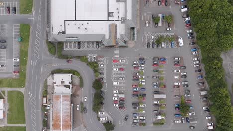 Top-down-view-of-a-nondescript-UK-supermarket-and-carpark,-showing-the-layout-of-the-parking-spaces,-cars,-and-surrounding-roads-and-buildings