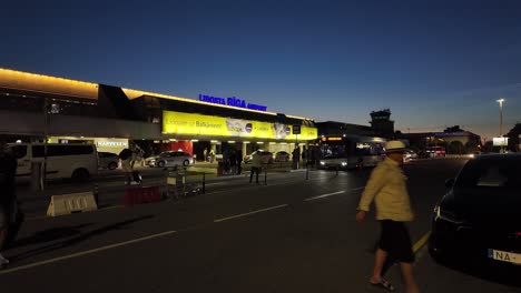 Nighttime-view-of-Riga-Lidosta-Airport-during-summer,-showing-people-arriving-at-parking-lot