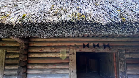 Straw-roof-detailed-view-and-people-entering-the-wooden-cabin-in-Estonian-Open-Air-Museum,-Tallinn