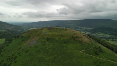 Dinas-Brân-castle,-legendary-home-of-the-Holy-Grail,-Wales---aerial-pull-back-from-far-on-a-moody-summer’s-afternoon