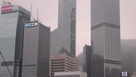 Hong-Kong-Cityscape,-Modern-Skyscrapers-In-Downtown-District-With-Foggy-Sky,-Tilt-Up