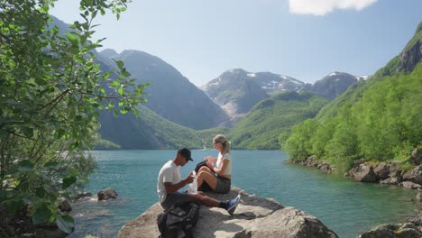 Couple-having-lunch-on-romantic-spot-near-Norway-lake,-static-view