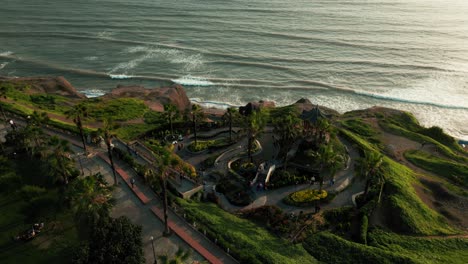 Aerial-images-show-a-Chinese-Theme-Park-in-Miraflores,-Lima,-with-a-gazebo,-gardens,-and-paths-facing-the-Pacific-Ocean-at-sunset,-blending-nature-and-architecture