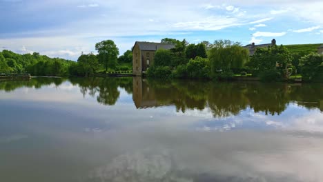 Drone-flying-over-water-surface-of-Mayenne-River-with-Saint-Baudelle-lock-or-weir,-France