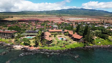 Drone-pans-up-from-ocean-to-reveal-Maui-beachfront-property,-fields,-and-volcano