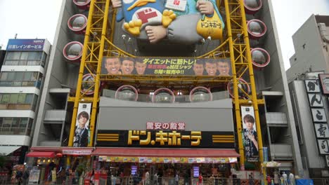 A-scenic-tilt-up-shot-capturing-the-iconic-Ferris-wheel-at-Don-Quijote-in-Dotonbori-from-across-the-river