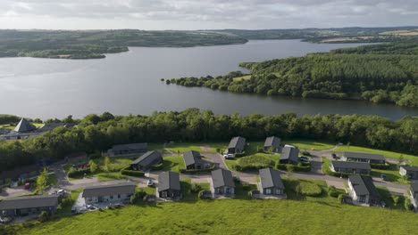 Drone-view-of-luxury-holiday-lets-by-a-lake-during-golden-hour-in-summer,-offering-a-picturesque-scene-in-Devon