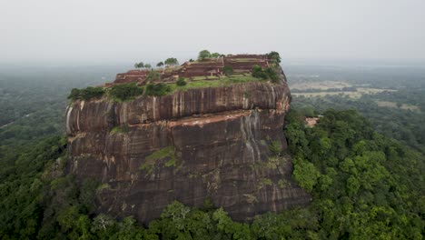 La-Antigua-Fortaleza-De-Roca-De-Sigiriya-Rodeada-De-Un-Exuberante-Bosque-Verde,-Vista-Aérea