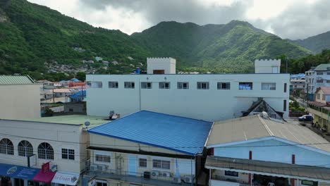 Aerial-approaching-shot-of-Soufriere-City-with-Gas-Station-and-cityscape-during-cloudy-day