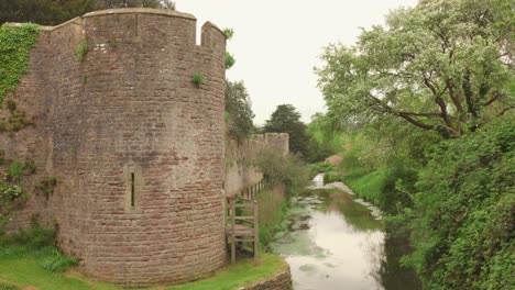 Ancient-stone-walls-and-a-peaceful-river-at-Bishop's-Palace-in-Wells,-England