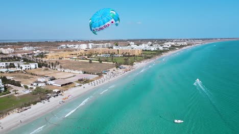 La-Imagen-Es-Una-Vista-Aérea-De-Una-Playa-Con-Agua-Azul-Cristalina-De-Un-Hotel-En-Mahdia,-Donde-La-Gente-Disfruta-De-Diversas-Actividades.