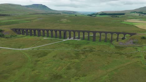 Ribblehead-viaduct-over-lush-green-fields-in-the-countryside,-aerial-view