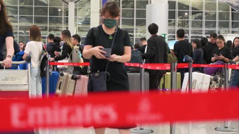 Flight-passengers-of-the-United-Arab-Emirates-airline,-Emirates,-are-seen-lining-up-at-a-check-in-desk-at-Chek-Lap-Kok-International-Airport