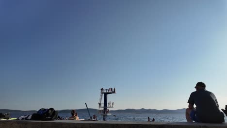 Jumping-board-on-the-beach-Kolovare,-Zadar,-Croatia-in-slow-motion-with-people-having-fun-in-summer