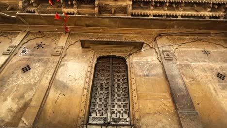 Tilt-up-shot-of-beautiful-ancient-structure-of-an-old-heritage-mansion,-carving-windows-made-up-of-yellow-limestone,-Kothari's-Patwon-Ki-Haveli-or-Patwa-Haveli-Jaisalmer-Rajasthan-India-4K