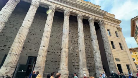 Tourists-visit-the-Temple-of-Hadrian-in-the-Campus-Martius-in-Piazza-di-Pietra-in-Rome,-Italy