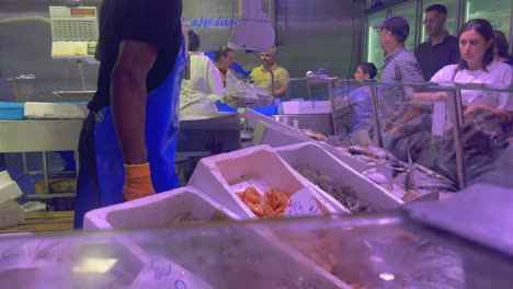 Vendors-and-shoppers-at-a-busy-seafood-market-in-Brussels,-fresh-fish-and-shrimp-on-display