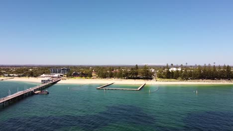 Wide-aerial-orbit-of-Busselton-beach-with-Jetty-and-swimming-enclosure-with-shark-nets