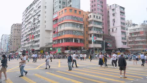 Wide-view-shot-of-multiple-busy-and-crowded-zebra-crossings-with-pedestrians-rushing-through-in-the-low-income-district-of-Sham-Shui-Po,-Kowloon,-Hong-Kong