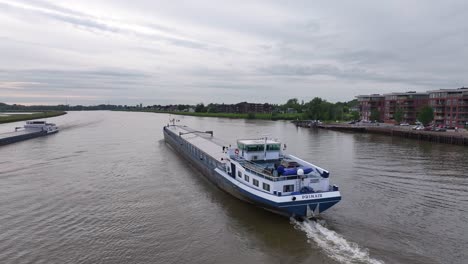 The-Primair-Cargo-Ship-is-Navigating-the-River-in-Alblasserdam,-South-Holland,-Netherlands---Tracking-Shot