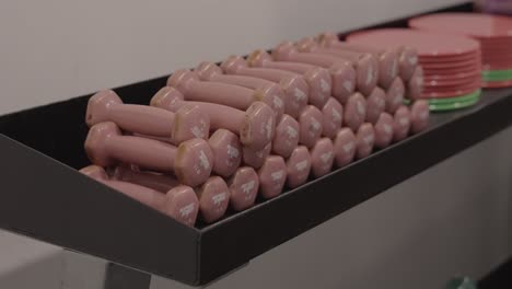 In-a-gym-setting,-observe-a-row-of-dumbbells-perfectly-aligned-on-a-rack,-seen-in-a-close-up-shot