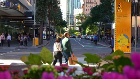 Urban-street-scene-capturing-cars-and-buses-passing-through-the-intersection-between-Edward-and-Queen-street-at-Brisbane-city's-central-business-district,-with-skyscrapers-on-both-sides,-slow-motion