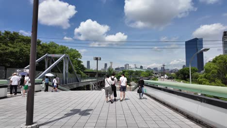 Gente-De-Pie-En-Una-Plataforma-De-Tren-De-Metro-Pasarela-Del-Horizonte-De-La-Ciudad-De-Osaka-En-Segundo-Plano.