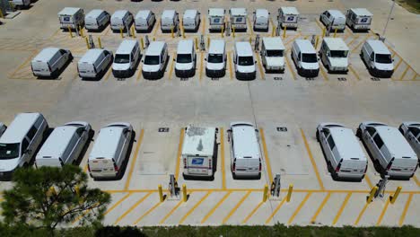 slowly-pushing-drone-shot-of-USPS-trucks-near-rows-of-newly-installed-chargers-behind-large-post-office