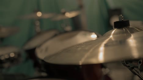 A-drummer-plays-their-kit-in-slow-motion,-with-a-shimmering-cymbal-in-focus-in-the-foreground