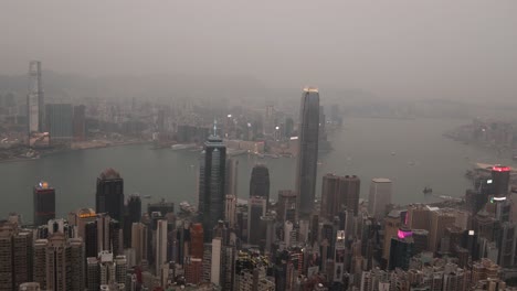 Skyline-Von-Hongkong-Bei-Nacht-Mit-Hellen-Lichtern-Der-Stadt,-Die-Sich-Im-Wasser-Spiegeln