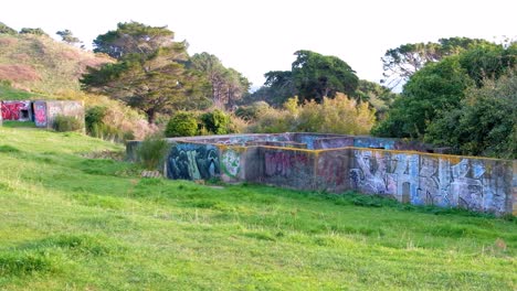 WW2-bunkers-with-graffiti-on-the-hillside-overlooking-harbour-at-The-Massey-Memorial-on-Point-Halswell-in-Wellington,-New-Zealand-Aotearoa