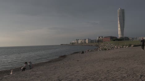 Ein-Sonnenuntergang-über-Einem-Strand-In-Malmö-Mit-Dem-Berühmten-Turning-Torso-Und-Der-Stadtlandschaft-Im-Hintergrund