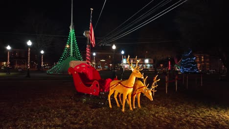 Aerial-orbit-reindeer-with-sleigh-and-american-flag-in-park-of-city-at-night