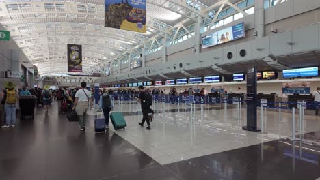 Travelers-queue-for-luggage-drop-and-check-in-at-the-Juan-Santamaría-International-Airport-entrance-terminal-in-San-Jose,-Costa-Rica