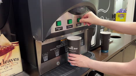 Woman-pressing-a-coffee-machine-button-pouring-English-Toffee-Cappuccino-in-cup-at-7-eleven-store-with-4k-resolution