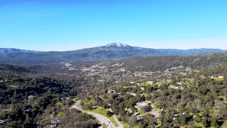 Vista-Aérea-Del-Parque-Nacional-De-Yosemite,-Colinas-Verdes,-Casas-Dispersas,-Montañas-Distantes,-Cielo-Azul,-Paisaje-Pintoresco,-Tranquilidad-De-La-Naturaleza,-Estados-Unidos