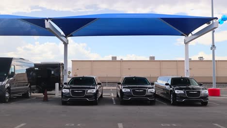 Black-limo-and-party-bus-vans-in-a-parking-lot-under-a-shade-sail-in-Las-Vegas