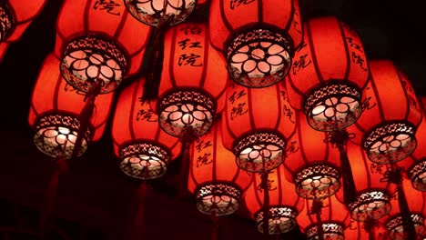 Chinese-Red-Lanterns-Hanging,-Illuminated-At-Night-With-Dark-Background,-Low-Angle