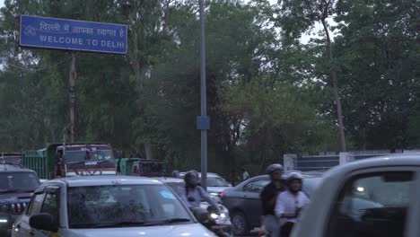 Tráfico-En-Kalindi-Kunj-Por-La-Noche-Con-Un-Cartel-Que-Dice-Bienvenido-A-Delhi