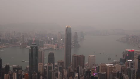 Hong-kong-skyline-with-skyscrapers-and-harbor-during-a-cloudy-day,-aerial-view