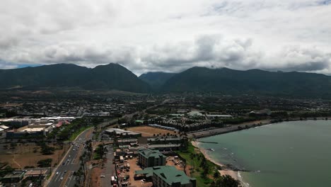 Wide-drone-shot-of-Kahului-city-Maui,-highway,-mountains,-and-ocean-with-clouds