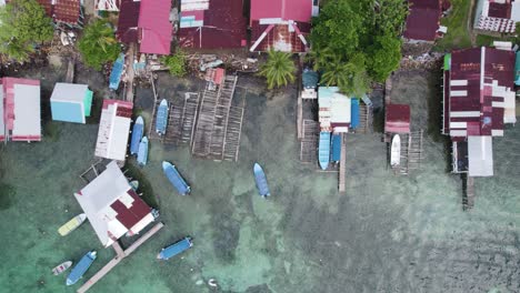 Aerial-birds-eye-view-of-colorful-boats-docked-along-the-shoreline-of-Bastimentos-Island-in-Bocas-del-Toro-District,-Panama