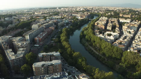 Drone-flies-along-winding-river-dividing-Trastevere-neighborhood-Rome-Italy,-establishing