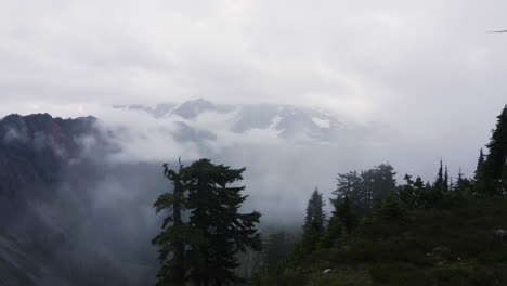 Timelapse-of-clouds-roll-and-push-up-against-mountain-ridgeline-moving-between-alpine-forest-in-PNW