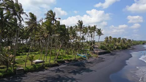 Traditional-Indonesian-outrigger-boats-sit-idle-on-secluded-beach,-aerial