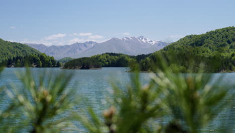 Mountain-lake-at-spring-snow-covered-mountains-background-Dolly-shot-slow-motion-sunny-day-clear-sky