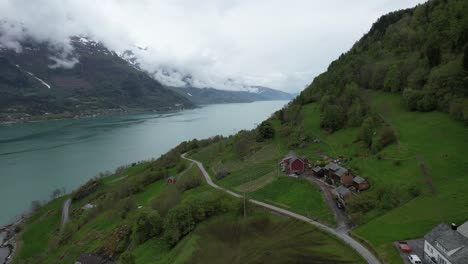 Norwegian-farm-on-the-side-of-a-fjord-on-a-gloomy-day-with-low-clouds-and-clear-blue-water-so-close