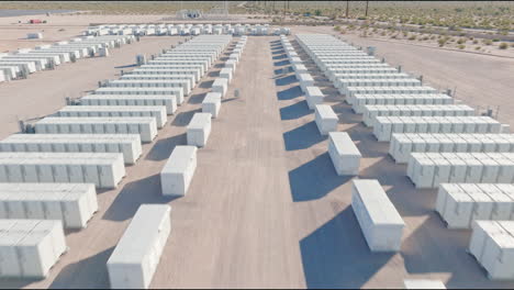 Drone-flying-through-rows-of-white-storage-units-at-an-outdoors-facility-in-the-desert