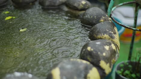 Estanque-De-Jardín-En-Tiempo-Lluvioso-Con-Ondas-De-Agua-Y-Gotas-De-Lluvia,-Cerrar